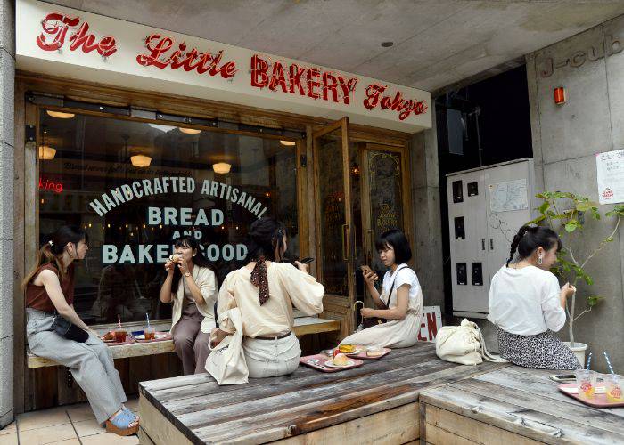 The exterior of Little Bakery Tokyo, where people are sitting down and enjoying coffee and donuts.